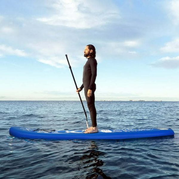 man standing on top of a paddle board in the middle of the ocean